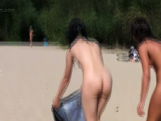 Nude beach girl sunbathes next to her man outdoors